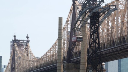 Fototapeta premium New York City Manhattan Midtown, Queensboro bridge architecture in United States. Urban public transport, tramway to Roosevelt island over East River. Red tram cabin car. Metallic bridge in East Side.