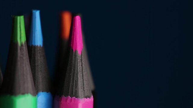 Colored pencils for drawing spin on a black background, stationery