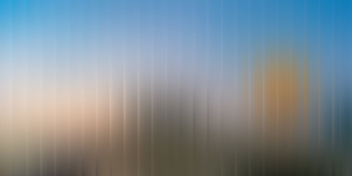 Blurred sun rays shining through vertical slats on a clear sky
