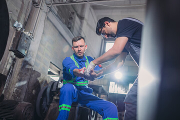 Fototapeta premium Factory Technician Receiving First Aid in Industrial Metal Workshop