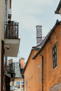 Low angle view of rustic yellow building wall with chimneys and balconies in historic European city