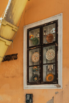 Traditional hand painted ceramic plates displayed in vintage window frame on rustic yellow wall