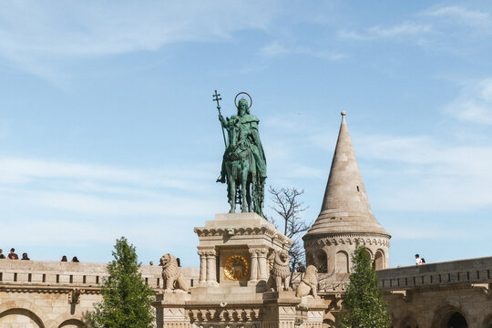 Bronze equestrian statue of king on pedestal near stone fortress turret