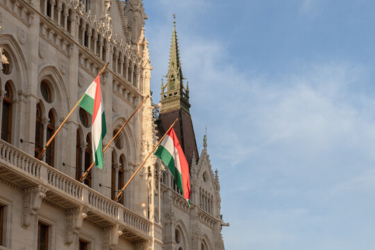 Hungarian flags on ornate neo-Gothic government building facade in warm sunlight