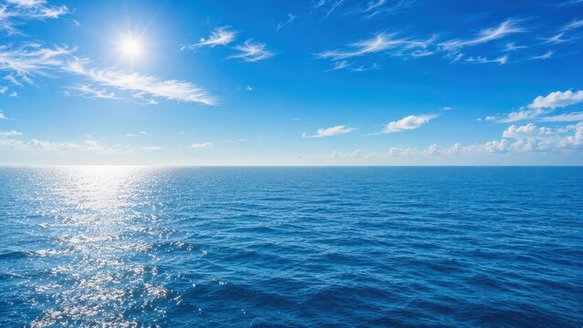 Bright sun shines over a vast, calm ocean under a blue sky with scattered clouds.