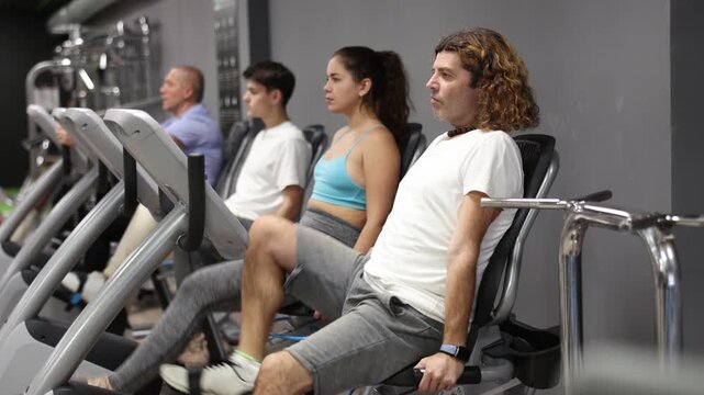 Focused sporty adult man working out on stationary bicycle in gym. Physical activity and fitness concept