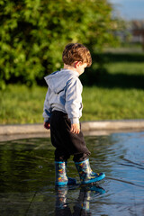 Fototapeta premium Child jumping into a puddle with colorful boots, capturing playful outdoor energy and motion