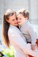 Fototapeta premium Mother holding her child closely outdoors, sharing a warm, affectionate moment in natural light