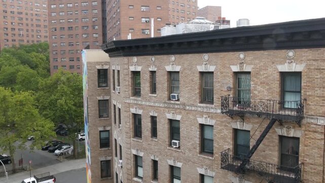 New York City urban residential buildings architecture, 125 street in Harlem, Manhattan, United States of America. Typical house in NYC, real estate property in USA. Fire escape metallic ladder.