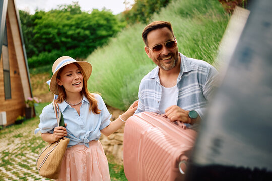 Happy couple preparing for summer road trip by car.