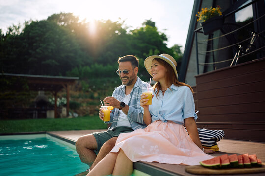 Happy couple enjoying in summer drink by pool during their vacation.