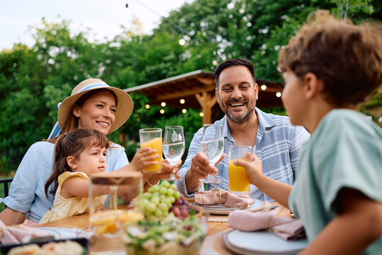 Happy parents and their kids toasting during family lunch on patio.