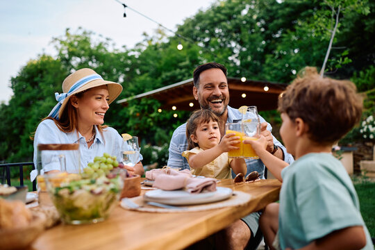 Cheerful family having fun while toasting at picnic table in backyard.