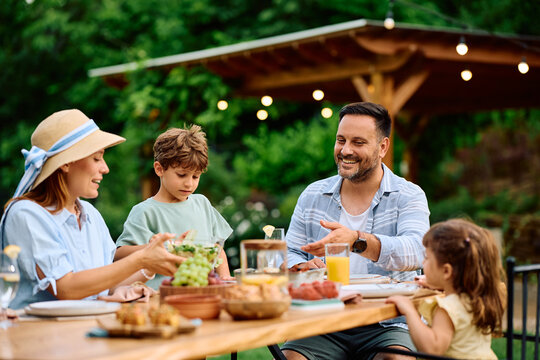 Happy family having lunch at picnic table on patio.