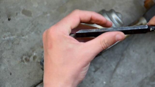 Close up of mechanic hands repairing wiper motor linkage with file in workshop