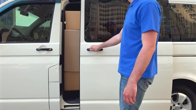 Delivery worker walks towards delivery van parked in bustling urban area. Professional delivery and urban logistics concept. Young man in blue uniform executes package drop-off