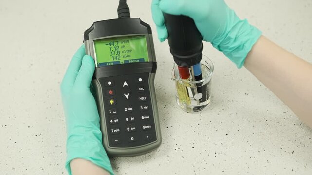 Laboratory water analysis using a combined pH meter and conductivity meter device. Scientific testing of water quality parameters including pH level and electrical conductivity in a laboratory
