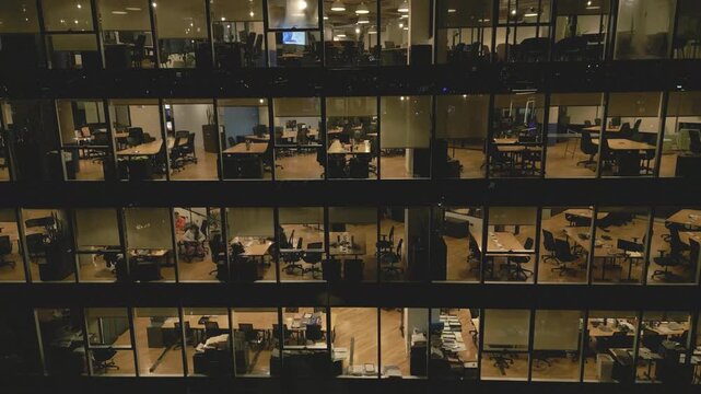 Offices at night with lights on and empty desks in the building