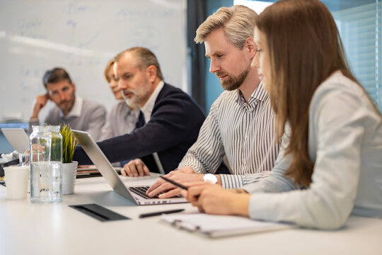 Successful businesspeople working in a coworking space working with laptop discussing strategy and business plan in modern office.