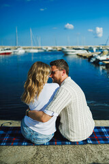Fototapeta premium Couple enjoys a quiet moment by the water with boats in the background in the afternoon sun