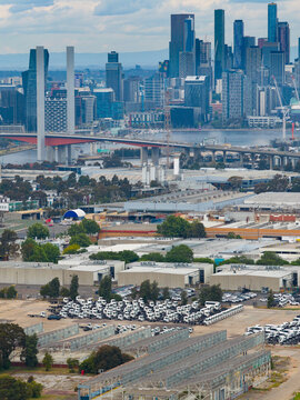 Aerial view of parked trucks and warehouses in front of a large bridge and a city skyline