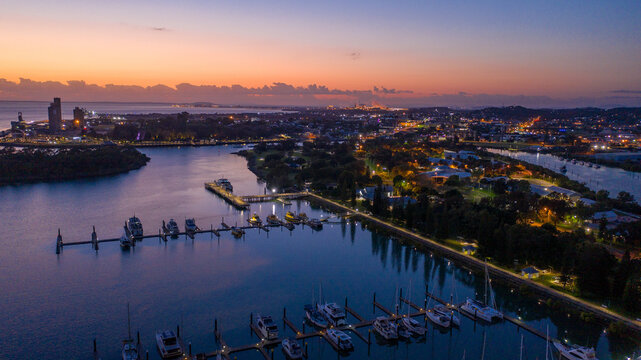 Rows of yachts and boats moored along illuminated piers at dusk