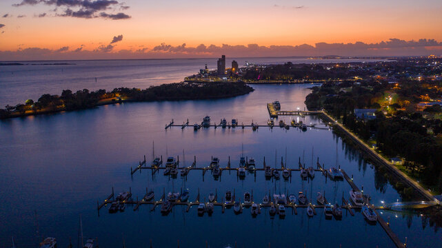 Rows of yachts and boats moored along illuminated piers at dusk