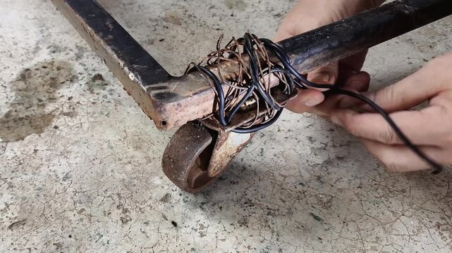 A man is fixing a cast-iron caster wheel, indoor Chiangmai Thailand.