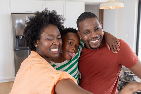 African American family taking selfie in home kitchen near stainless steel refrigerator and pot