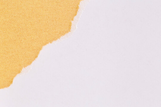 white sheet of paper with torned corner against golden cardboard
