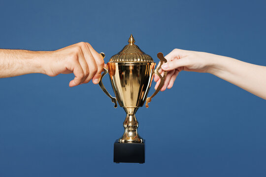 Close up cropped male female holding in hand football soccer golden champion cup isolated on pastel plain light blue color wall background studio. Sport award concept. Copy space advertising mock up.