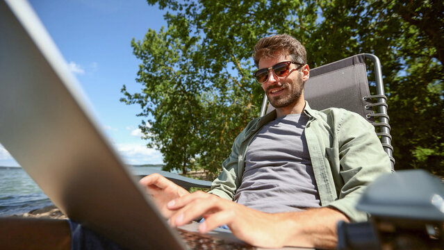 A man is sitting on a chair with a laptop in front of him