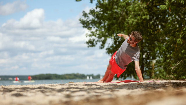 A man is doing a push up on the beach