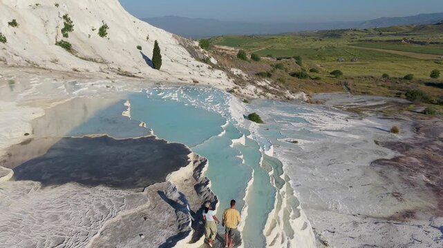 Discover the breathtaking beauty of Pamukkale in Turkey, where natural hot springs form stunning terraces. A couple strolls through the warm, turquoise waters surrounded by picturesque landscapes.