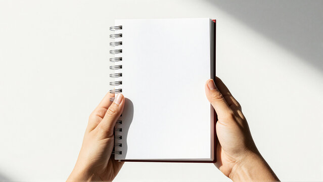 Hands holding open blank spiral notebook for notes