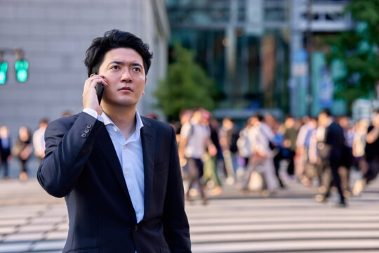 帰宅ラッシュ時のオフィス街の交差点でスマートフォンで深刻な連絡をうけてショックで落ち込む会社員の男性