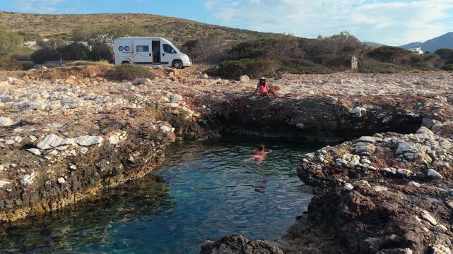 A couple swimming in a natural pool at Paros Island, Greece where crystal-clear waters meet unique rock formations. A perfect spot for relaxation and enjoying the stunning natural landscape.
