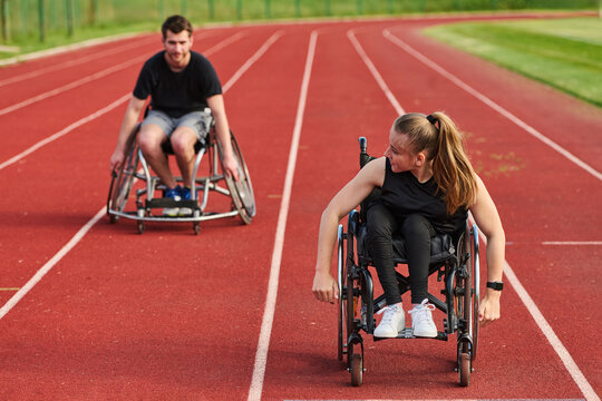 Two Wheelchair Athletes Racing on Outdoor Track Practicing Paralympic Training and Competitive Sports