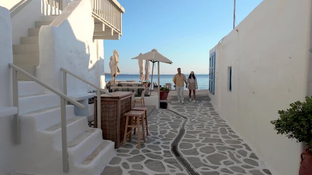 A couple wanders through the picturesque streets of Paros, Greece, where charming cafes and stunning views meet warm sunshine. Experience the atmosphere and vibrant culture of this Cycladic paradise.