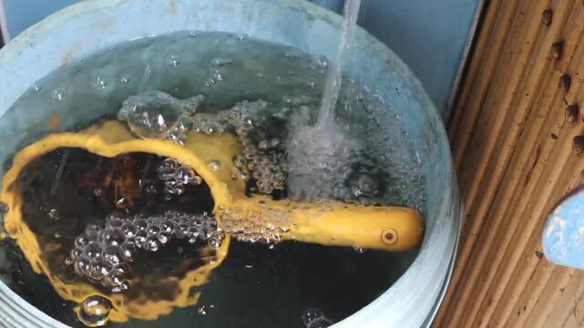 Fresh water flows into a basin while a kitchen strainer is being cleaned during food preparation.