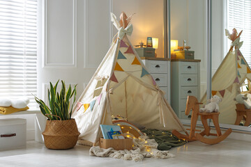 Cute wigwam with fairy lights and toys in stylish child's room © New Africa