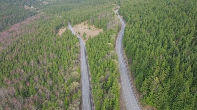 Drone flies backward above forest road junction with vehicles in Rodnei Romania