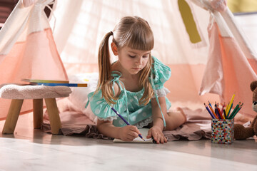 Little girl drawing near wigwam at home © New Africa