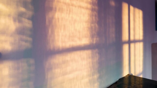 Timelapse of golden hour sunlight caustics and window shadow moving on wall