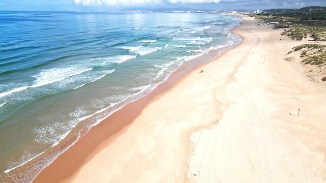 Aerial view of Praia da Morena coastline with gentle waves and sparse beachgoers
