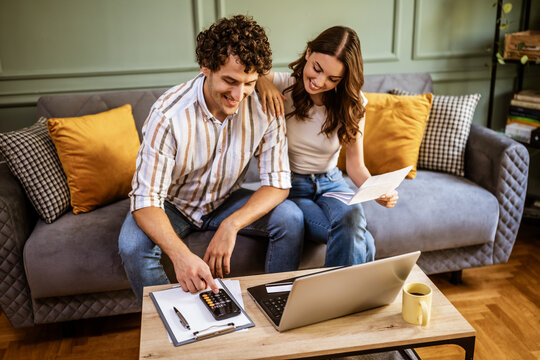 Young couple calculating home finances while checking bills.
