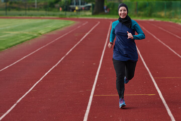 Fototapeta premium Smiling Female Runner Wearing Headscarf Jogging On Outdoor Track For Fitness And Health