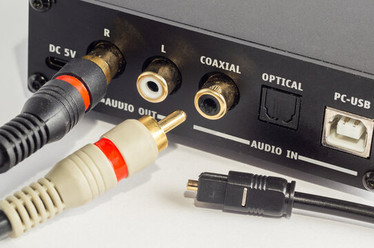 Close-up of RCA connectors plugged into an audio device and an optical cable.