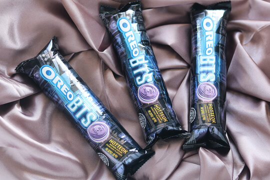 Tangerang, Indonesia - June 7, 2026: Three limited edition Oreo BTS collaboration snack wrapper packs are displayed on a reflective purple cloth.