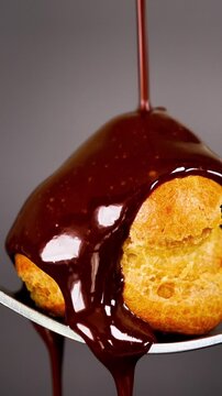 chocolate sauce pouring over profiterole choux pastry close up